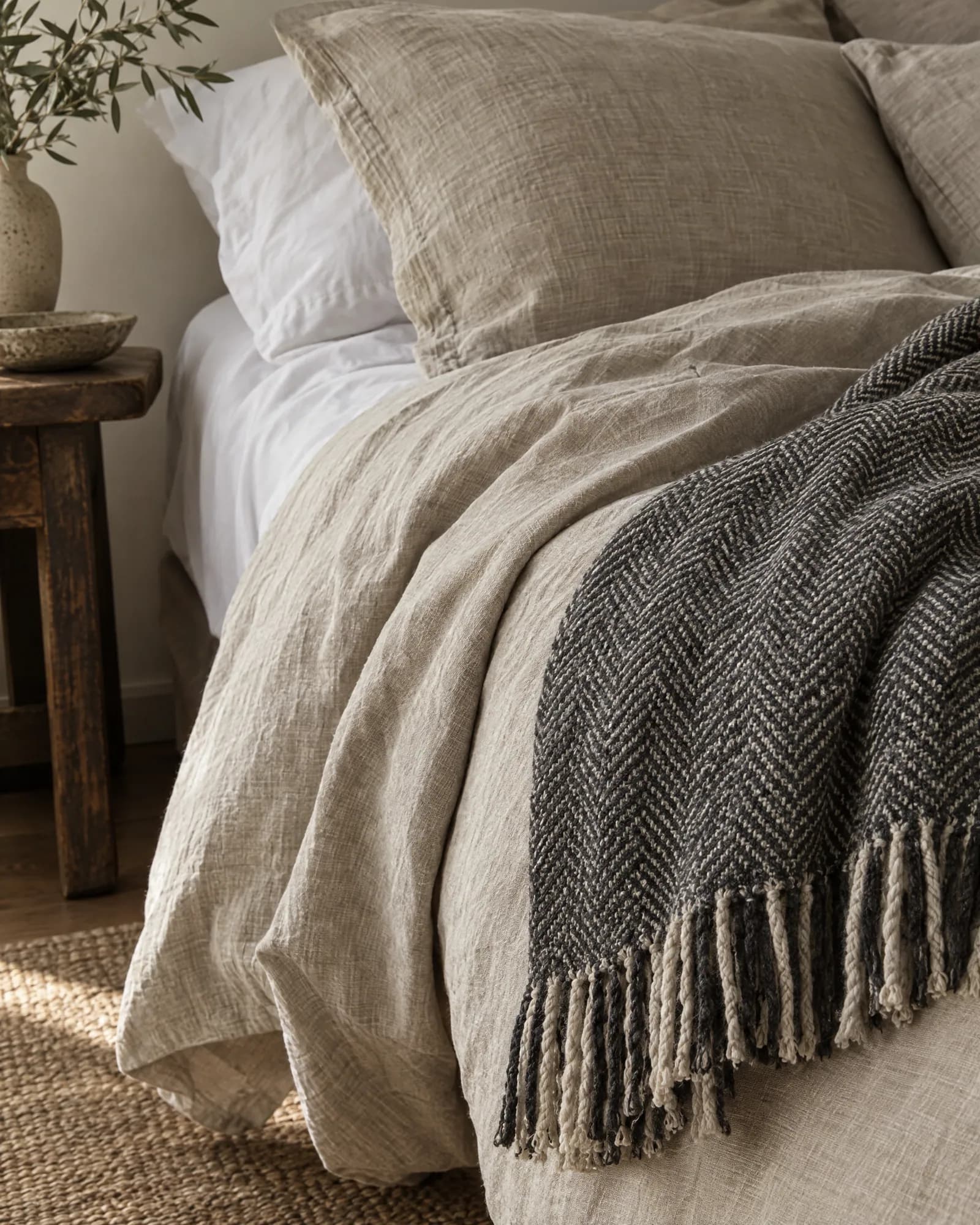 Stonewashed linen bedding with a herringbone wool throw draped over the edge